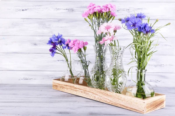Beautiful summer flowers in vases on grey wooden background — Stock Photo, Image