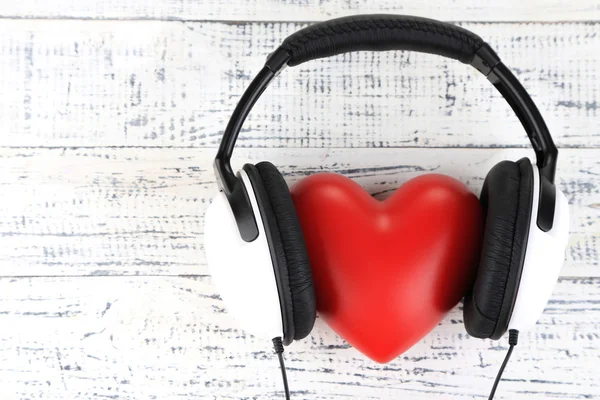 Auriculares y corazón sobre fondo de madera — Foto de Stock