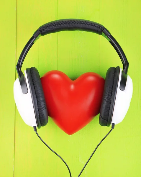 Sluchátka a srdce na barevné dřevěné pozadí — Stock fotografie