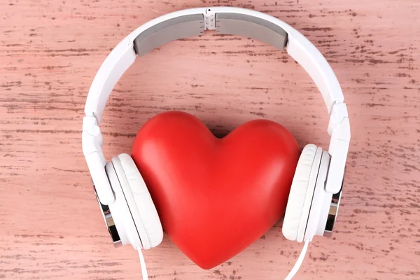 Auriculares y corazón sobre fondo de madera de color — Foto de Stock