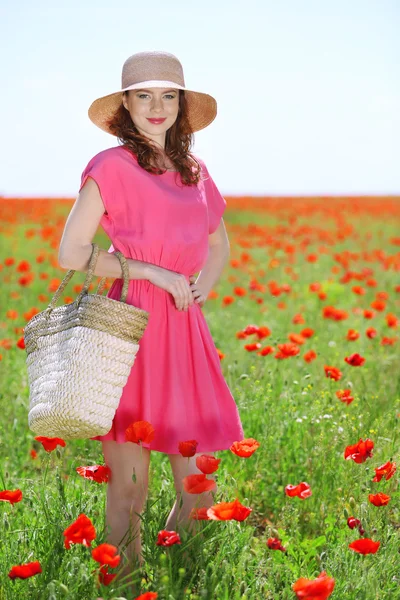 Piękna młoda kobieta trzyma wiklinowe torby w pole Maków — Zdjęcie stockowe