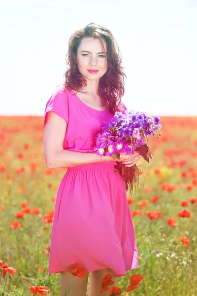 Bella giovane donna con fiori nel campo di papavero — Foto Stock