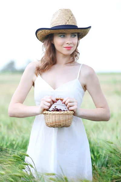Hermosa joven mujer sosteniendo canasta de mimbre con cerezas en el campo —  Fotos de Stock