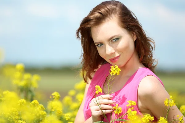 Hermosa joven en el campo de flores — Foto de Stock