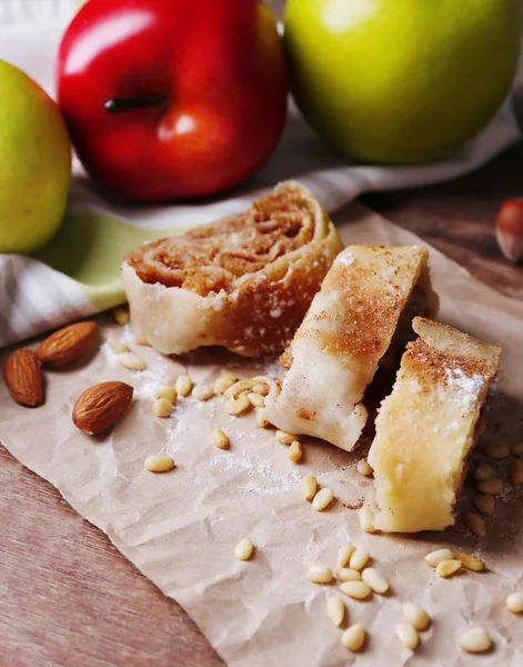 Вкусный домашний яблочный штрудель на бумажной салфетке, на деревянном фоне — стоковое фото
