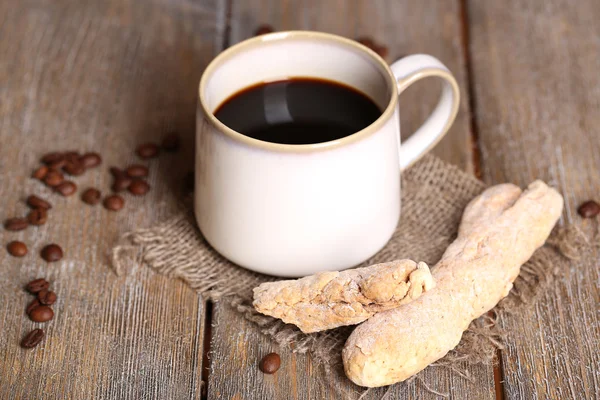 Cangkir dengan kopi panas di kain karung serbet, di atas meja kayu latar belakang — Stok Foto