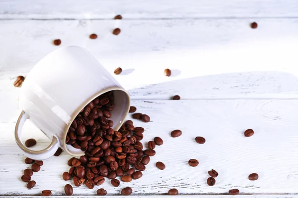 Tasse mit gerösteten Kaffeekörnern auf Holztischhintergrund — Stockfoto