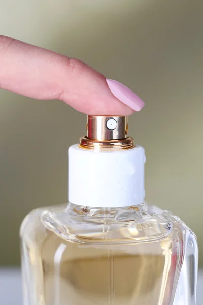 Botella de perfume en mano sobre fondo brillante — Foto de Stock