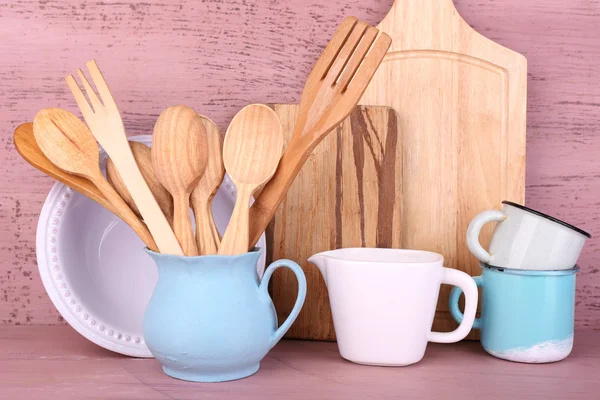 Склад дерев'яних столових приборів, сковороди, чаші та обробної дошки на дерев'яному фоні — стокове фото
