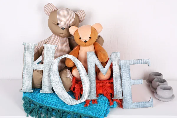 Letras decorativas formando palabra HOME con oso de peluche sobre fondo de pared — Foto de Stock