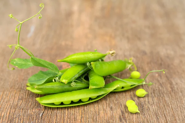Fresh green peas on wooden table — Stock Photo, Image