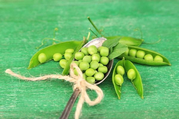 Frische grüne Erbsen im Löffel auf Holztisch — Stockfoto