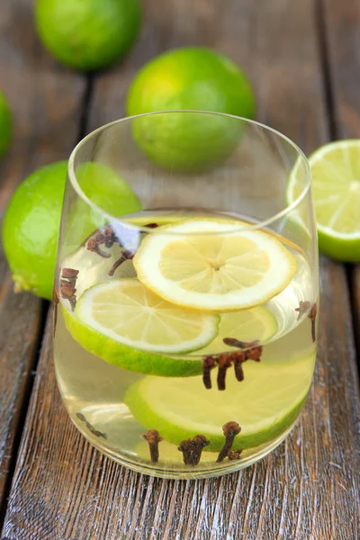 Bebida fresca de verano con lima y clavo de olor en vidrio, sobre fondo de madera de color — Foto de Stock