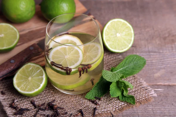 Bebida fresca de verano con lima y clavo de olor en vidrio, sobre fondo de madera de color —  Fotos de Stock