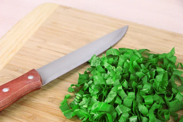 Chopped greens with knife on cutting board — Stock Photo, Image