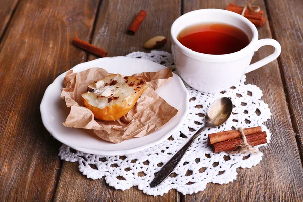 Peras al horno con jarabe en plato y taza de té sobre fondo de madera de color —  Fotos de Stock