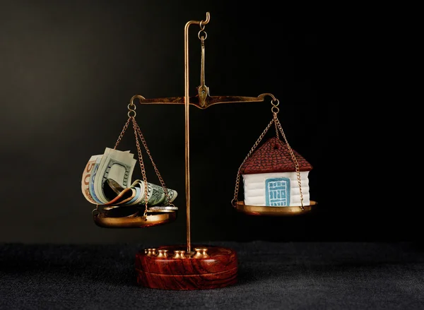 Scale with money and model of house on dark background — Stock Photo, Image