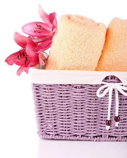 Color towels and lily flowers in wicket basket, isolated on white — Stock Photo, Image