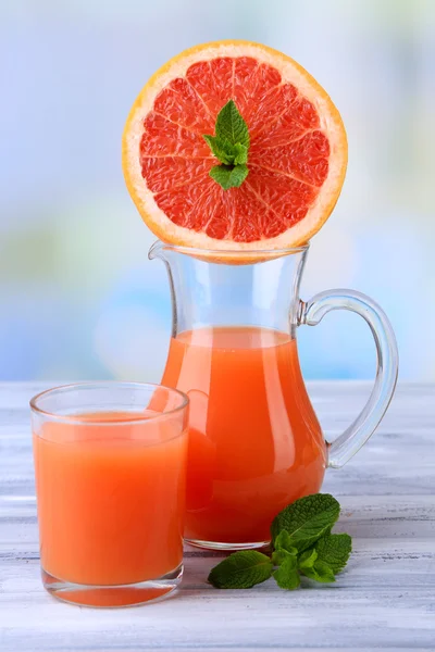 Grapefruitsaft in Glas und Krug auf farbigem Holzhintergrund — Stockfoto