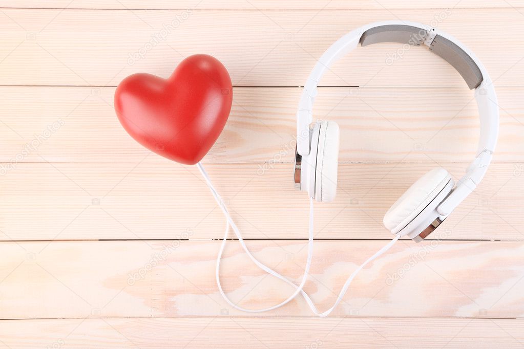 Headphones and heart on wooden background