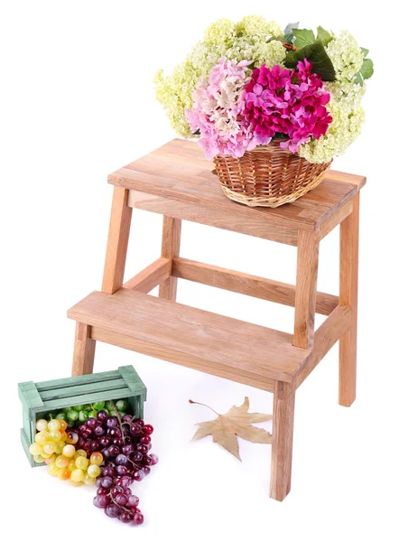 Wicker basket with flowers and fruits in wooden box,  on small wooden ladder, isolated on white — Stock Photo, Image