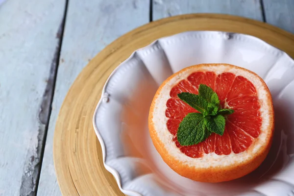 Mogen grapefrukt på plattan på färg trä bakgrund — Stockfoto