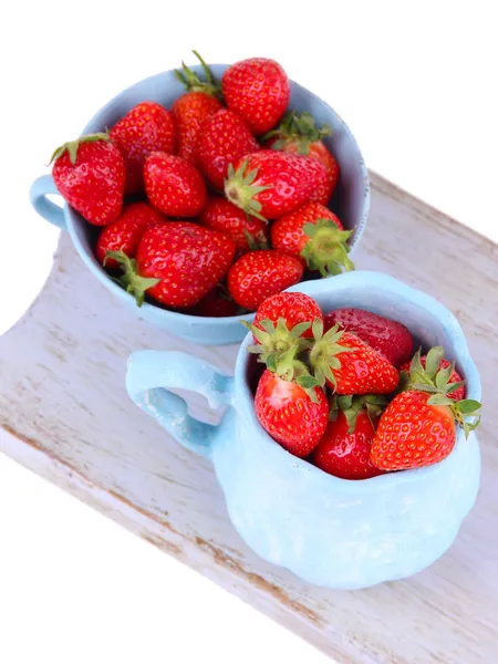 Rijpe zoete aardbeien in kleur mokken op snijplank geïsoleerd op wit — Stockfoto