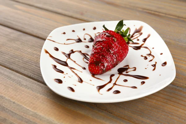 Red ripe strawberry with chocolate on wooden table — Stock Photo, Image