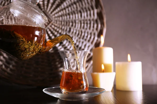 Herbata, wlewając do filiżanki szkło na ciemnym tle — Zdjęcie stockowe