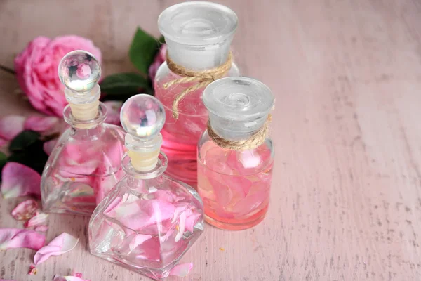 Olio di rosa in bottiglie su sfondo di legno di colore — Foto Stock