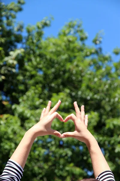 Jeune fille tenant la main en forme de coeur encadrant sur fond de nature — Photo
