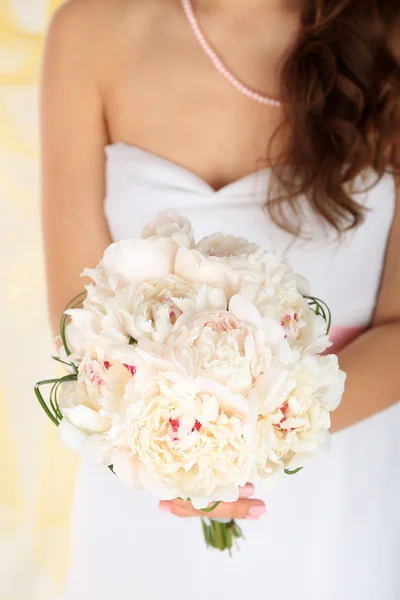 Bruid houden bruiloft boeket van witte pioenrozen, close-up, op lichte achtergrond — Stockfoto