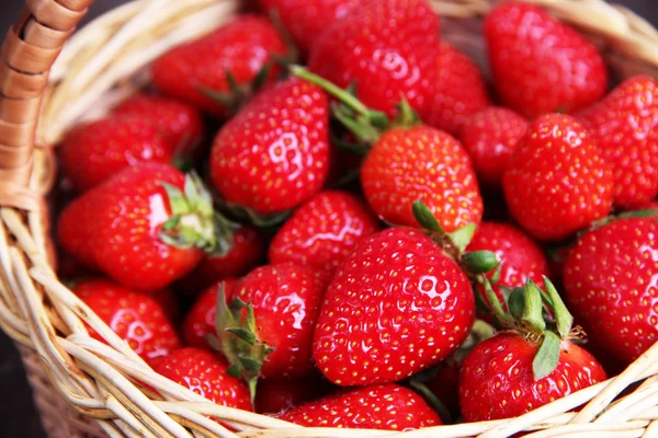 Ripe sweet strawberries in wicker basket on wooden background — Stock Photo, Image