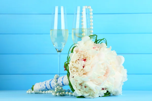 Schöner Hochzeitsstrauß und Weingläser auf farbigem Hintergrund — Stockfoto