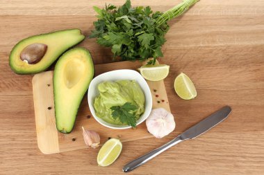 Fresh guacamole in bowl on wooden table clipart