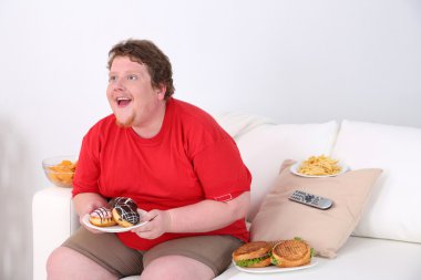 fast food kanepede oturuyor ve televizyon izlerken tembel kilolu erkek