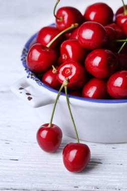 Tatlı kirazlar ahşap arka planda renkli kasede