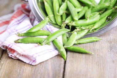 ahşap zemin üzerine kevgir içinde taze yeşil bezelye