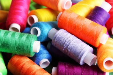 Multicolor sewing threads on wooden background clipart
