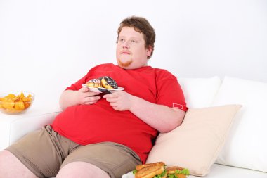 fast food kanepede oturuyor ve televizyon izlerken tembel kilolu erkek