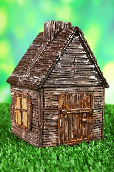 Small wooden house on grass on bright background — Stock Photo, Image