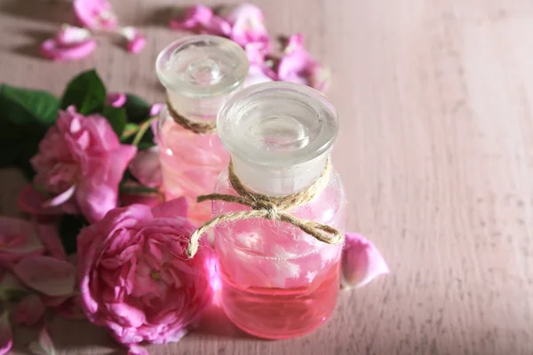 Olio di rosa in bottiglia su sfondo di legno di colore — Foto Stock