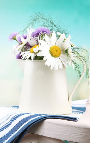 五颜六色的花朵在装饰的水桶，在椅子上，在明亮的背景上的花束 — 图库照片