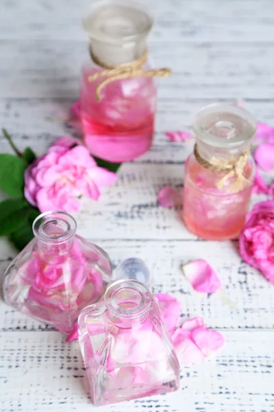 Růžového oleje v lahvích na barevné dřevěné pozadí — Stock fotografie