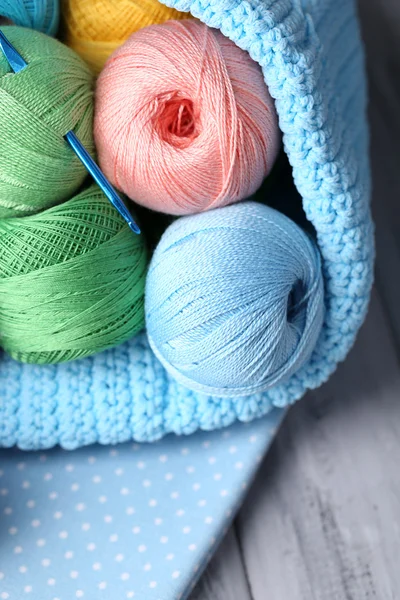 Colorful clews, napkin and crochet hook in basket on wooden background — Stock Photo, Image