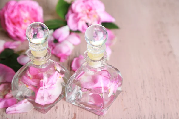 Rose oil in bottles on color wooden background — Stock Photo, Image