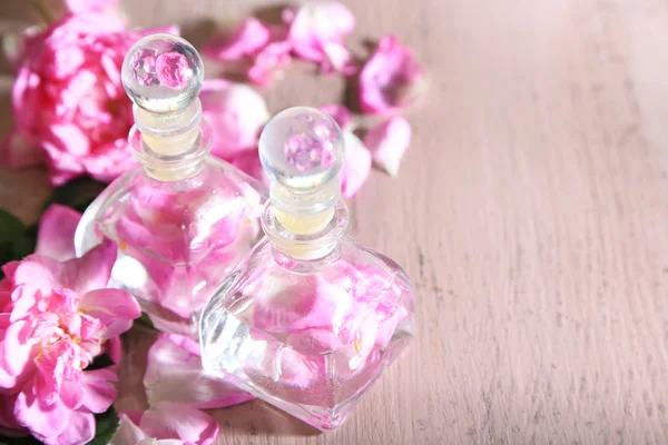 Olio di rosa in bottiglie su sfondo di legno di colore — Foto Stock