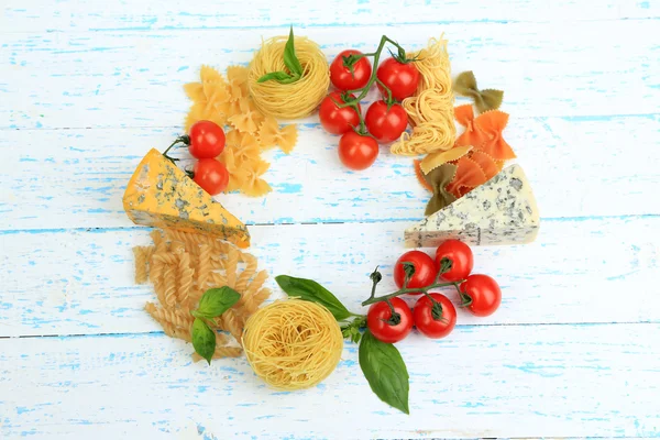 Různé těstoviny, sýra a rajčat na dřevěný stůl detail — Stock fotografie
