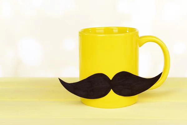 Cup with mustache on table on light background — Stock Photo, Image