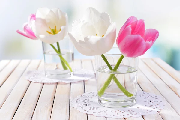 Hermosos tulipanes en cubo en jarrón sobre mesa sobre fondo claro — Foto de Stock